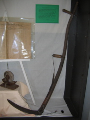 Shown here is the long handled scythe with an attached brace to accommodate its length. Donated by  Bob Faught.
